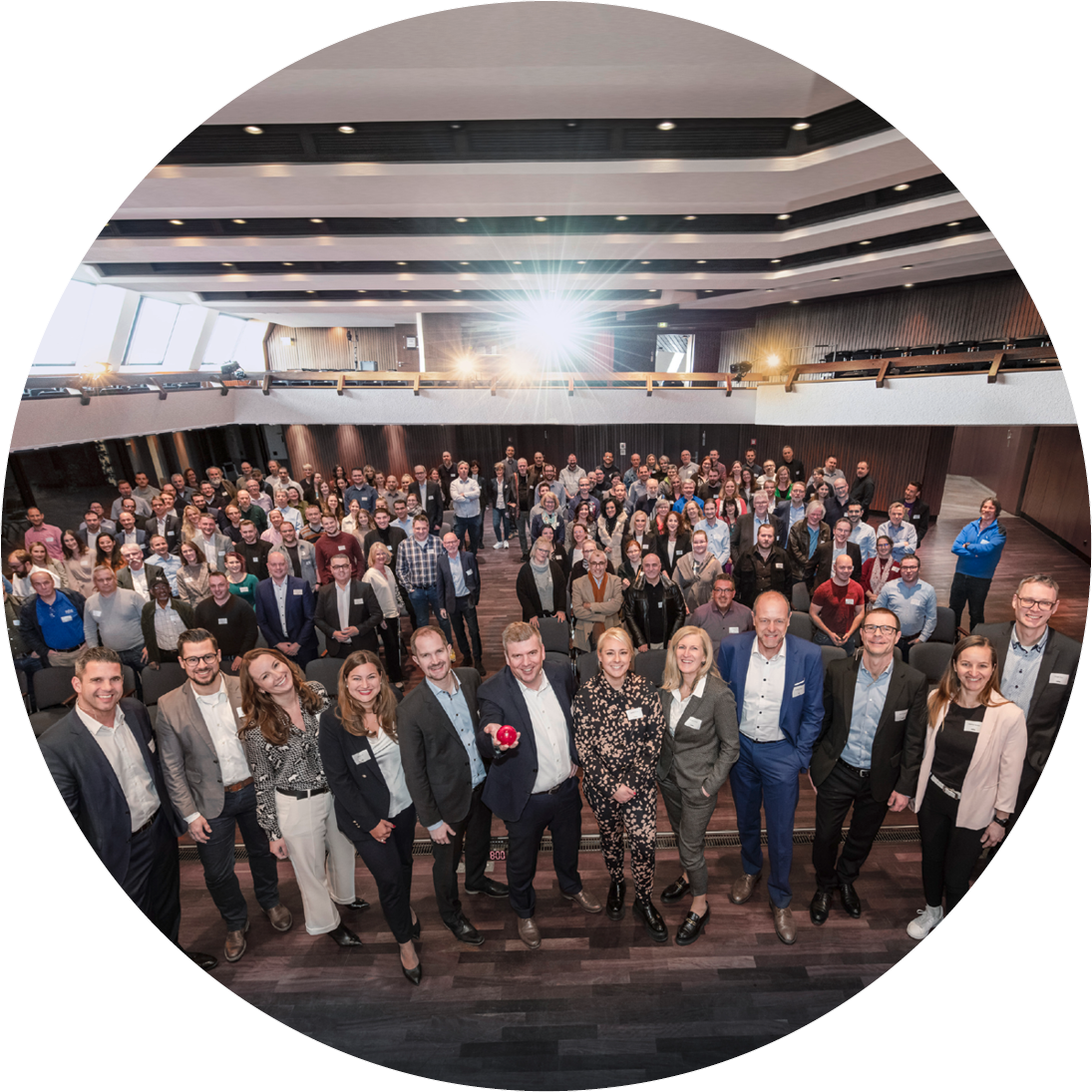 Große Gruppe von audius Mitarbeitern und Führungskräften bei einer Firmenveranstaltung in einem modernem Auditorium – Symbol für Teamgeist und Qualitätsversprechen.