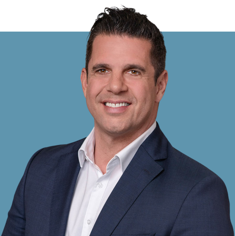 Porträt von Konstantin Tsaligopoulos, Vorstandsmitglied der audius SE, lächelnd in dunklem Sakko und weißem Hemd vor blauem Hintergrund.