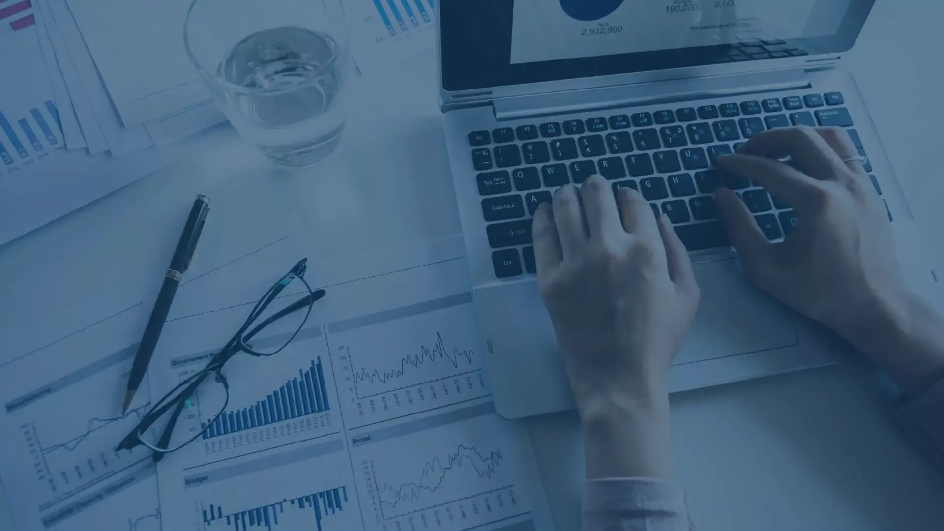 Hände tippen auf Laptop-Tastatur zur Verarbeitung von Buchhaltungsdaten.