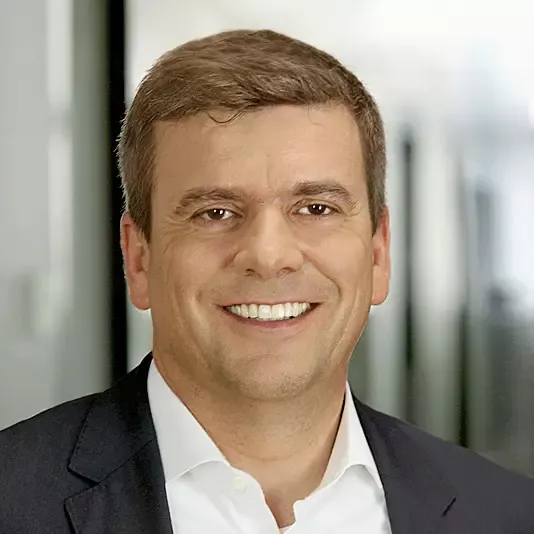 Porträt von Rainer Francisi, Vorstandsmitglied der audius SE, lächelnd in dunklem Sakko und weißem Hemd.