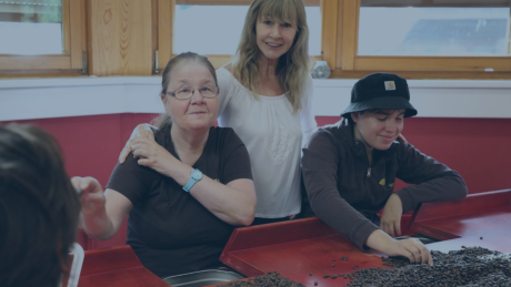 Drei Personen in der Rösterei Laufenmühle sortieren gemeinsam Kaffeebohnen – ein Symbol für Nachhaltigkeit, Inklusion und verantwortungsvollen Kaffeegenuss bei audius.